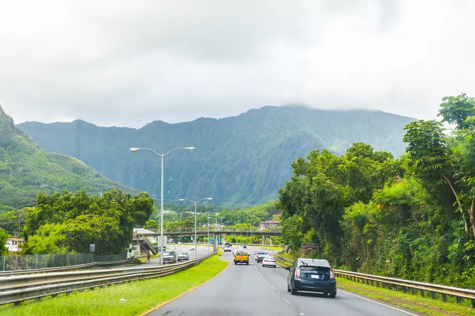 Traffic on Hawaii highway with green mountains in background